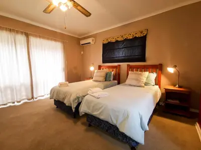 a bedroom with two beds and a large window at Loerie Guesthouse in Hoedspruit