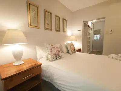 a bedroom with a white bed with a lamp on a table at Loerie Guesthouse in Hoedspruit