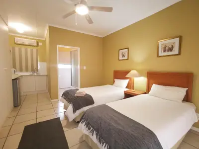a hotel room with two beds and a bathroom at Loerie Guesthouse in Hoedspruit