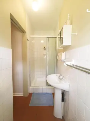 a white bathroom with a sink and a shower at Loerie Guesthouse in Hoedspruit