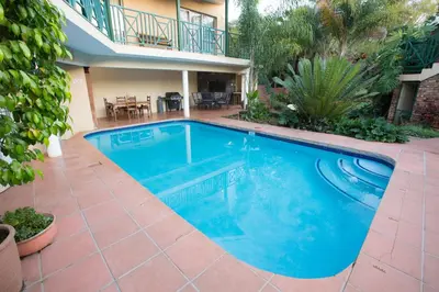 a swimming pool in a yard with a house at Loerie Guesthouse in Hoedspruit