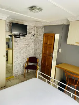 a room with a bed and a tv on a wall at Northgatelodges and Tours in Polokwane