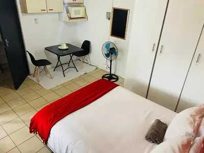 a bedroom with a bed and a table and chairs at Northgatelodges and Tours in Polokwane