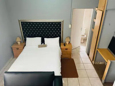 a bedroom with a large bed and a toilet at Northgatelodges and Tours in Polokwane