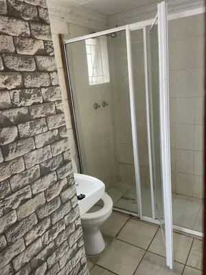 a bathroom with a toilet and a stone wall at Northgatelodges and Tours in Polokwane