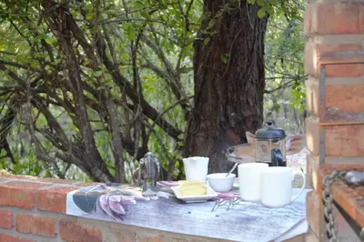 a table with cups and dishes on a brick wall at At Kruger's Heartbeat in Marloth Park