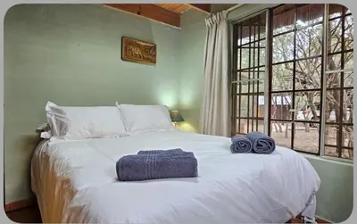 a bedroom with a large white bed with two towels on it at At Kruger's Heartbeat in Marloth Park