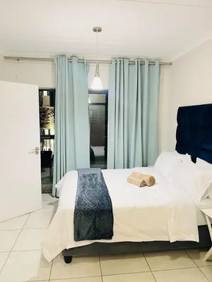 a bedroom with a large bed with blue curtains at The blyde apartment in Pretoria