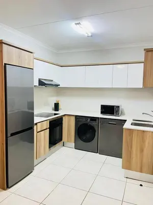 a kitchen with stainless steel appliances and wooden cabinets at The blyde apartment in Pretoria