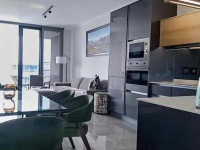 a kitchen with a table and chairs and a living room at Ellipse Waterfall Executive Two Bedroom in Midrand