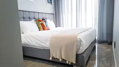 a bedroom with a bed with white sheets and pillows at Ellipse Waterfall Executive Two Bedroom in Midrand