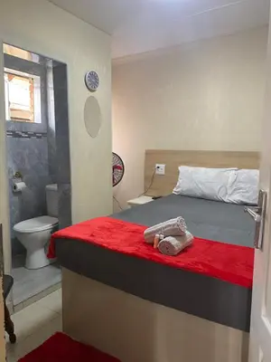 a bedroom with a bed and a bathroom with a toilet at Maoba GuestHouse in Soshanguve