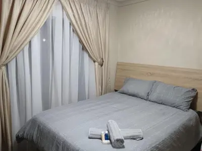 a bedroom with a bed with two stools on it at Maoba GuestHouse in Soshanguve