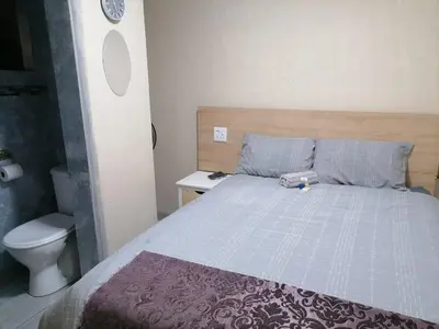 a bedroom with a bed and a toilet in it at Maoba GuestHouse in Soshanguve