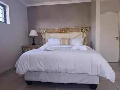 a bedroom with a large bed with white sheets and pillows at Calm house by the river in Brits