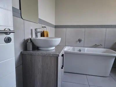 a bathroom with a white sink and a white tub at Calm house by the river in Brits