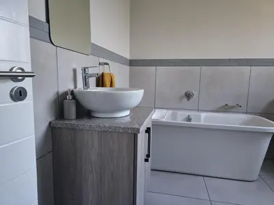 a bathroom with a white sink and a white tub at Calm house by the river in Brits