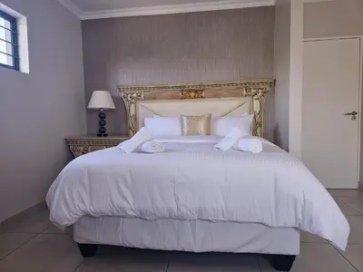 a bedroom with a white bed with a gold headboard at Calm house by the river in Brits