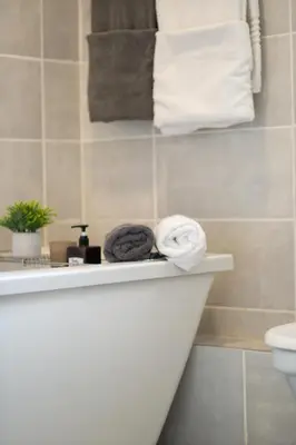 a bathroom with a toilet and towels on a shelf at The Blyde- Feel At Home in Pretoria