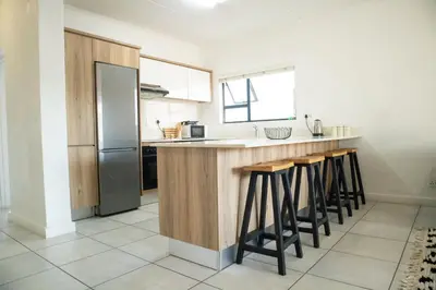 a kitchen with a counter with stools and a refrigerator at The Blyde- Feel At Home in Pretoria