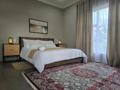 a bedroom with a bed and a large window at Muca House in Thohoyandou