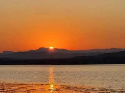 a sunset over a body of water with the sun setting at Muca House in Thohoyandou