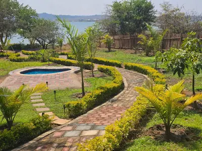 a garden with a brick path leading to a pool at Muca House in Thohoyandou