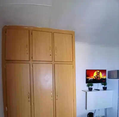 a room with wooden cabinets and a tv on a wall at The Serenity in Polokwane