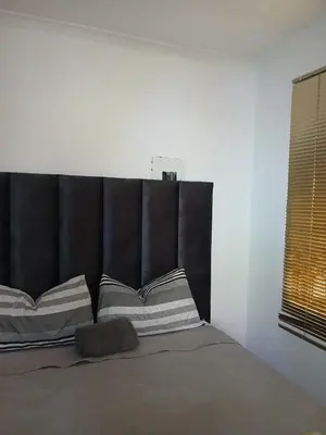 a bed with a black headboard and some pillows at The Serenity in Polokwane