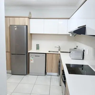 a kitchen with white cabinets and a refrigerator at Blyde Cozy-TEE'S Apartment in Pretoria