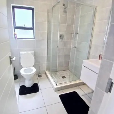 a bathroom with a shower and a toilet and a sink at Blyde Cozy-TEE'S Apartment in Pretoria