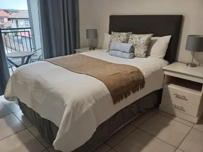 a bedroom with a large bed and a balcony at Blyde Cozy-TEE'S Apartment in Pretoria