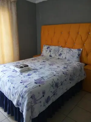 a bed with an orange headboard and a blanket at Day & Night Guestrooms in White River
