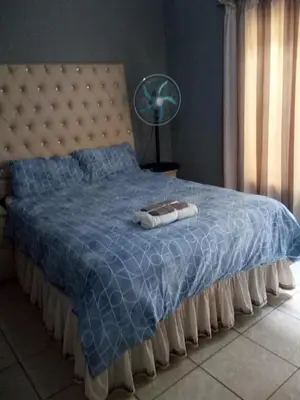 a bed with a blue blanket and a fan at Day & Night Guestrooms in White River