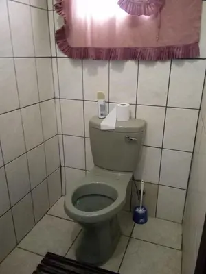a bathroom with a toilet in a tiled room at Day & Night Guestrooms in White River