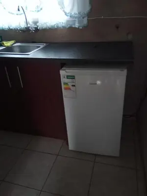 a small refrigerator under a counter next to a sink at Day & Night Guestrooms in White River