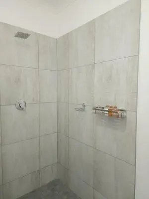 a bathroom with a shower with a large stone wall at Bohemian Escape Midrand in Midrand