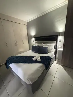 a bedroom with a large bed with blue and white pillows at Nettle Nest Accommodation in Polokwane