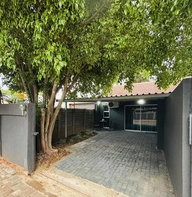 a house with a tree and a brick driveway at Nettle Nest Accommodation in Polokwane