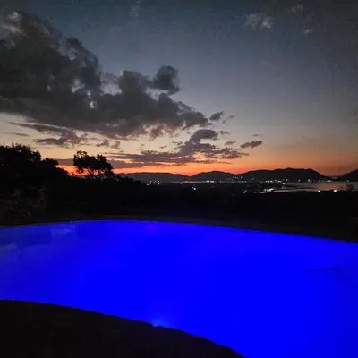 a blue swimming pool with a sunset in the background at Katima Mountain View Lodge in Hartbeespoort
