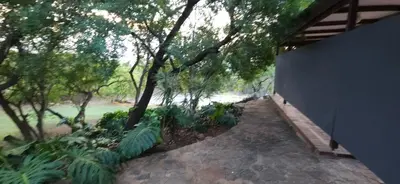 a walkway through a forest with trees and a fence at Katima Mountain View Lodge in Hartbeespoort