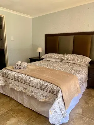 a bedroom with a large bed with a large headboard at Katima Mountain View Lodge in Hartbeespoort