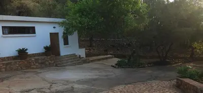 a white house with a stone wall next to a driveway at Katima Mountain View Lodge in Hartbeespoort