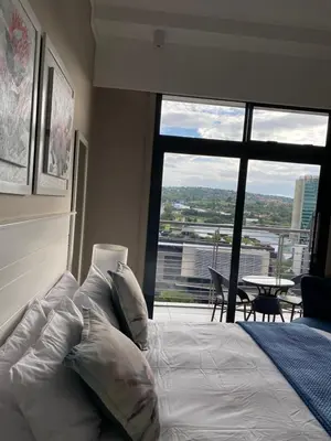 a bedroom with a bed and a large window at Menlyn Maine Trilogy Apartment in Pretoria