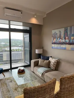 a living room with a couch and a glass table at Menlyn Maine Trilogy Apartment in Pretoria