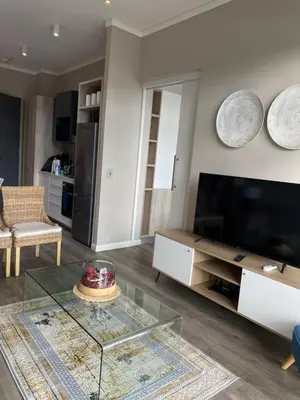 a living room with a glass table and a television at Menlyn Maine Trilogy Apartment in Pretoria