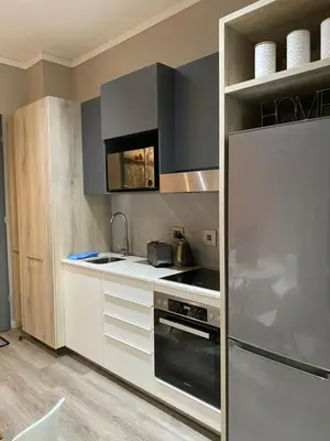 a kitchen with a stainless steel refrigerator and white cabinets at Menlyn Maine Trilogy Apartment in Pretoria