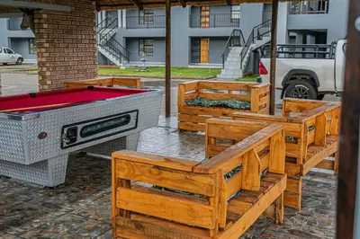 a group of wooden benches with a pool table at Mahlakwena Crown Crest in Steelpoort