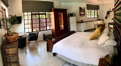 a bedroom with a large white bed and a kitchen at Piano Inn in Centurion