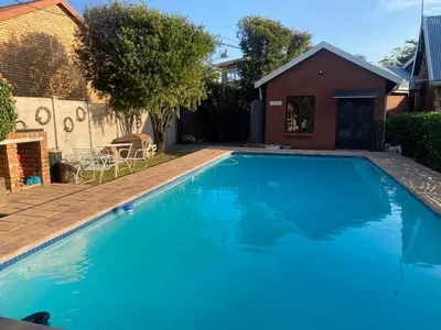 a large blue swimming pool in front of a house at Piano Inn in Centurion